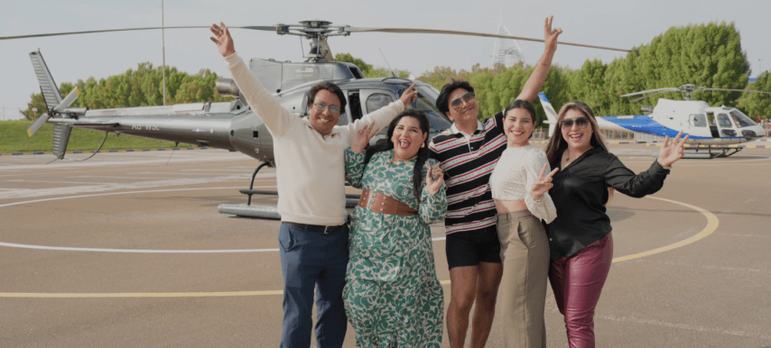 A family poses for a photo in front of a helicopter during their private helicopter tour.