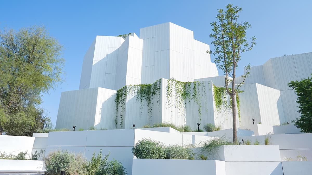 Natural History Museum Abu dhabi adorned with various green plants growing on its exterior.