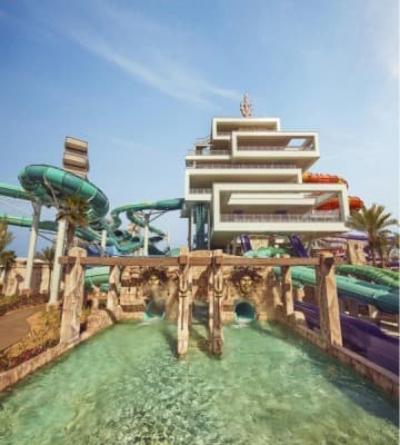 A vibrant water park at Atlantis Dubai featuring a large slide and an impressive building in the background.
