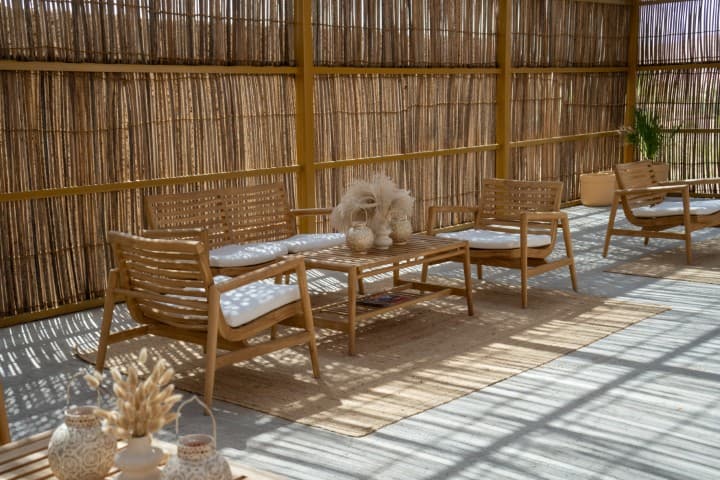 A cozy room featuring wooden furniture and a bamboo wall, designed for Mleiha Buggy Camp seating.