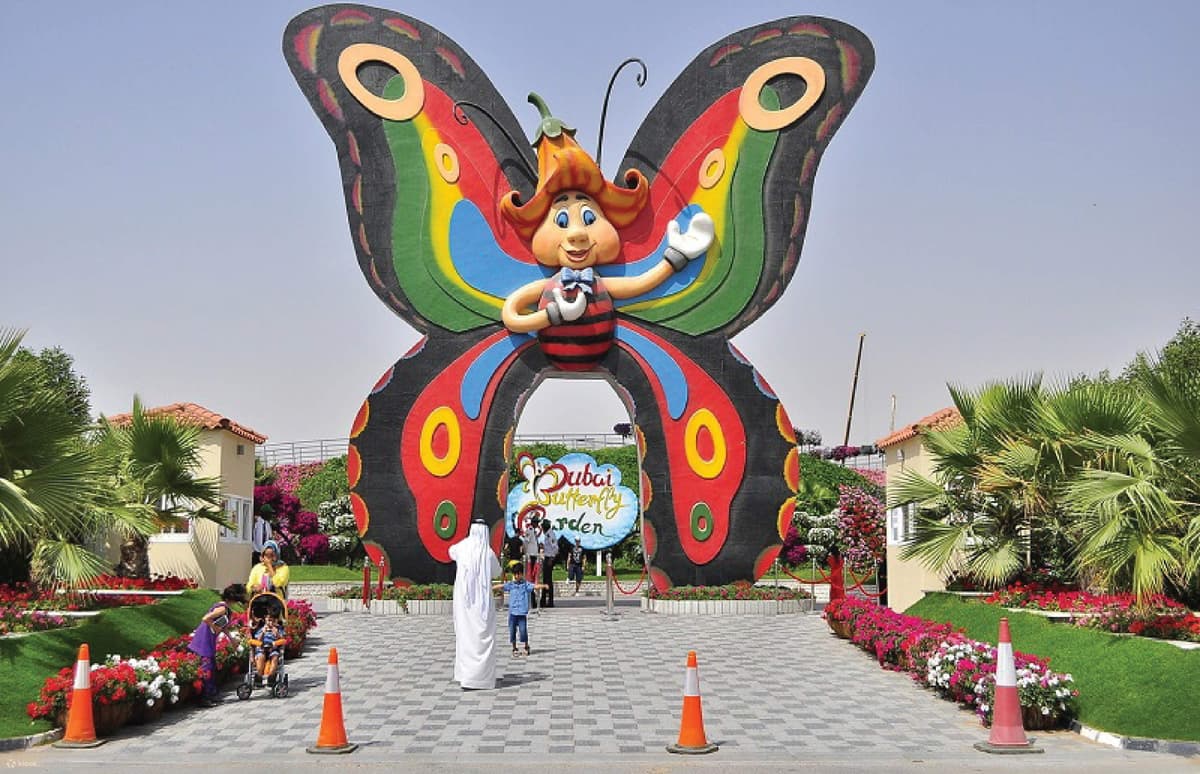 Main entrance of the Dubai Butterfly Garden with colorful butterfly-themed decorations and visitors arriving.