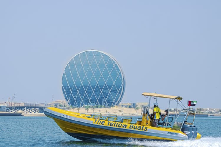 A yellow and black boat near the Yellow Boats Abu Dhabi Coin Building, showcasing vibrant colors against the skyline.