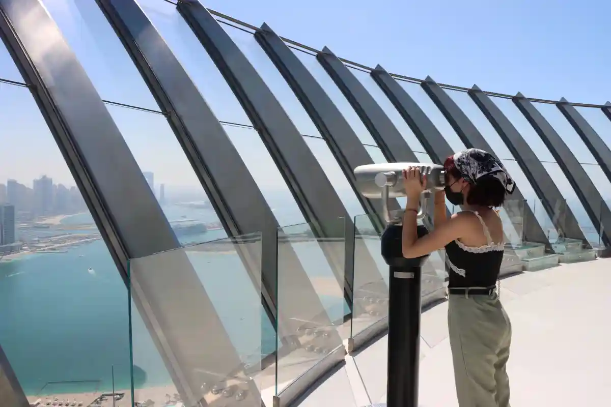 Guest using a telescope at The View at The Palm observation deck to see Palm Jumeirah from above.