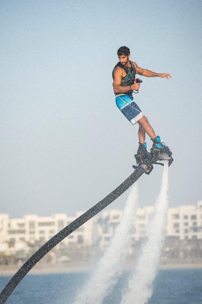A man performing tricks on a jet ski in the water, showcasing skills as a Flyboard Dubai Trainer.