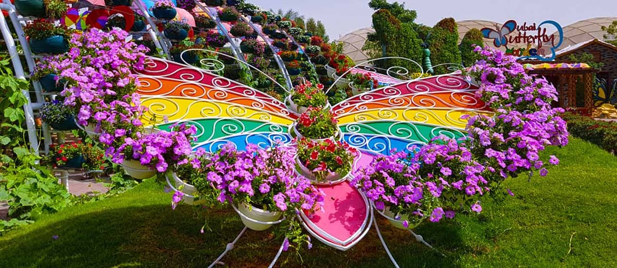 Colorful butterfly-themed arch design inside the Dubai Butterfly Garden surrounded by flowers