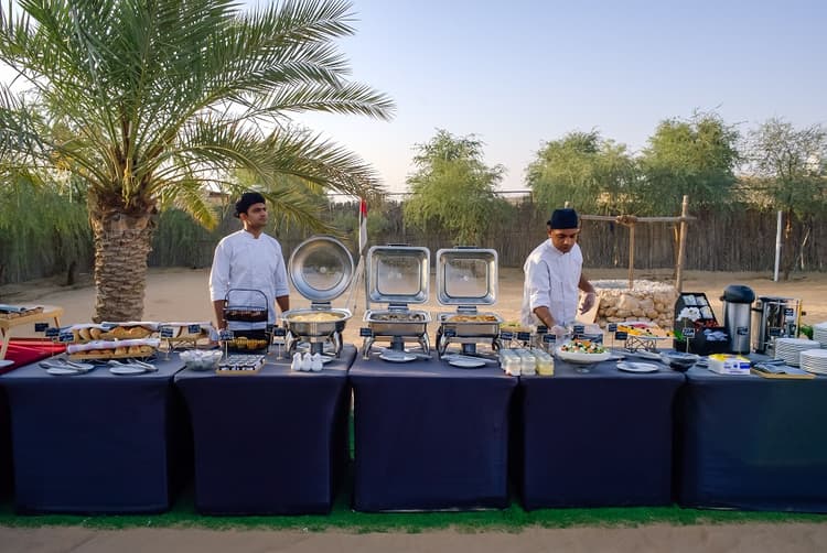 Guests enjoying a buffet breakfast in the desert after a hot air balloon ride in Dubai