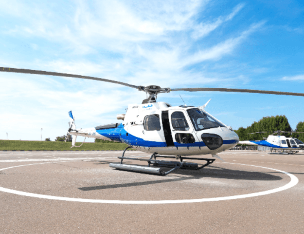 A private helicopter parked on the tarmac, ready for a tour, with a helipad visible in the background.