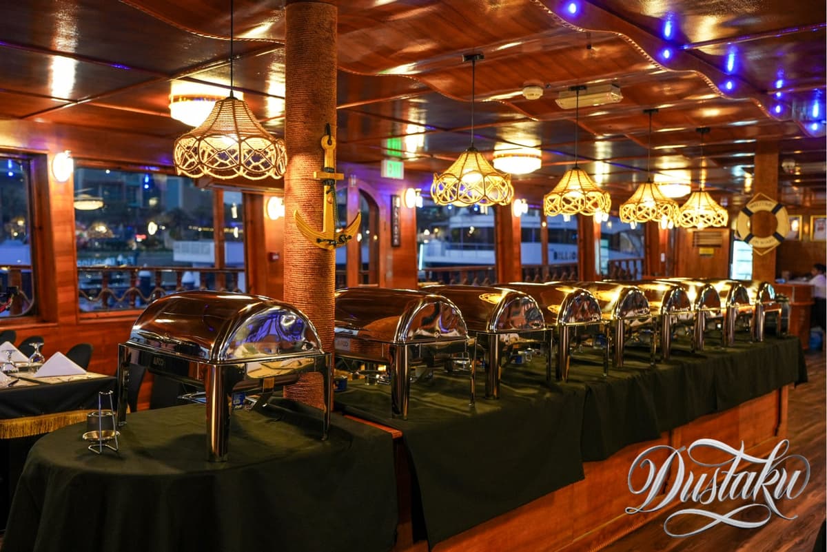 A restaurant deck featuring tables and chairs, set for the Dustaku Dinner Dhow Cruise Buffet.