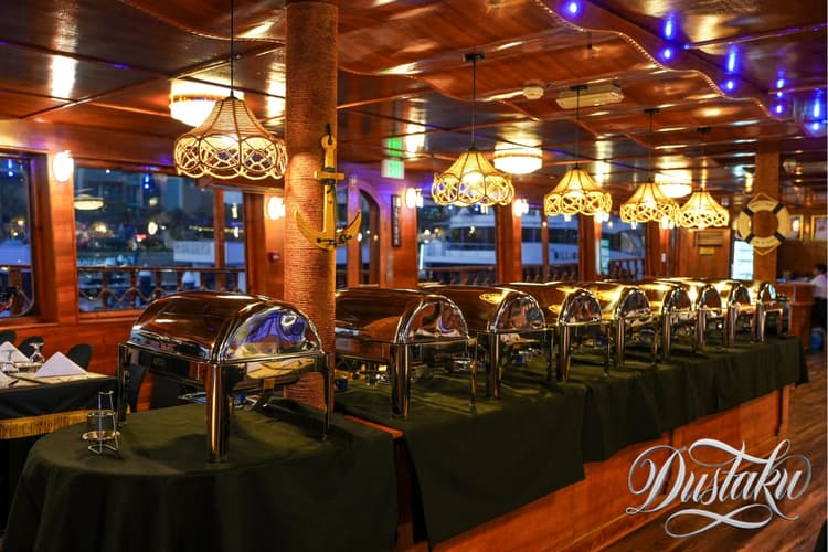A restaurant deck featuring tables and chairs, set for the Dustaku Dinner Dhow Cruise Buffet.